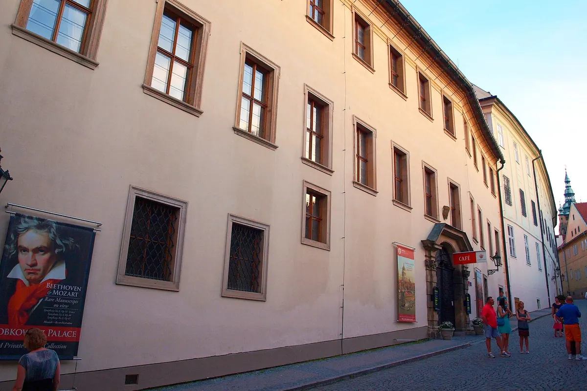 The street front of the Lobkowicz Palace with a poster of Beethoven beside the entrance and cobbles in the foreground