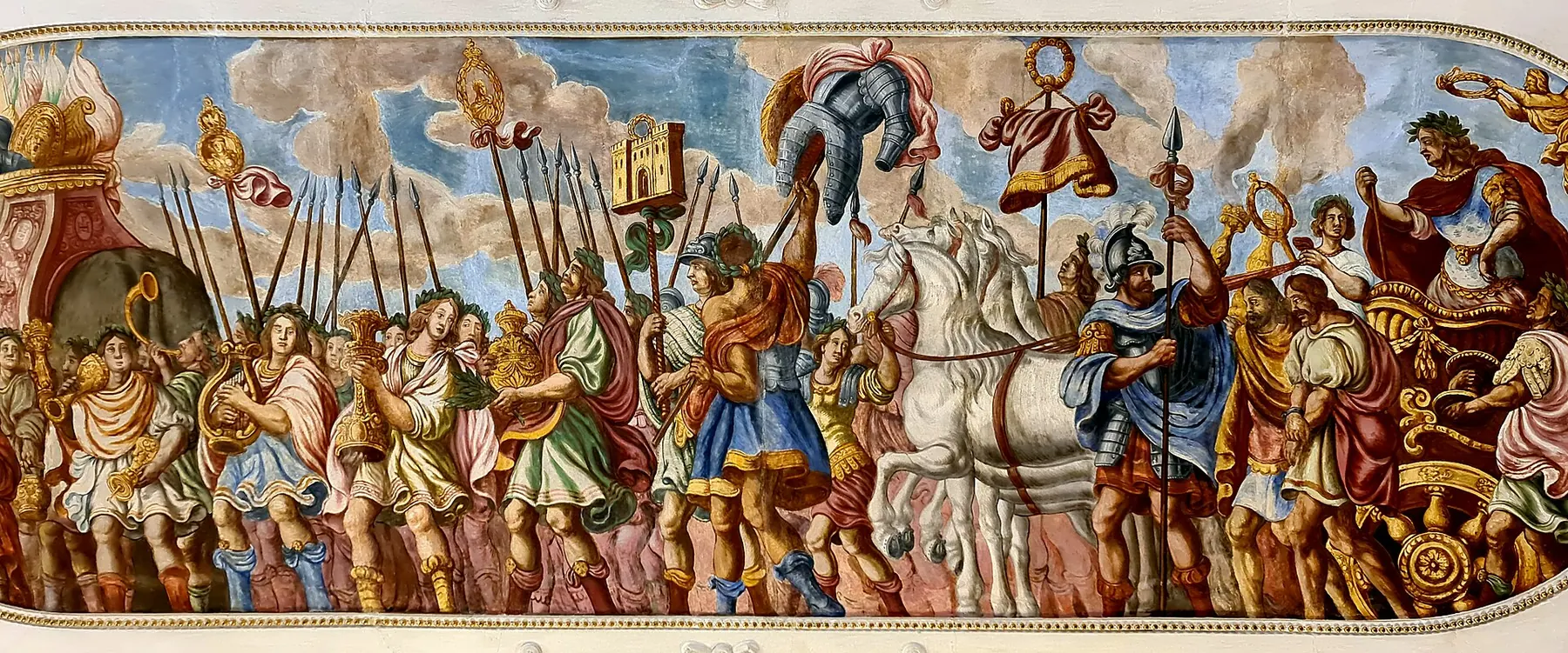 A long painted ceiling fresco in the Lobkowicz Palace showing a triumphal procession of figures in antique dress with spears and banners, with white horses at the centre.