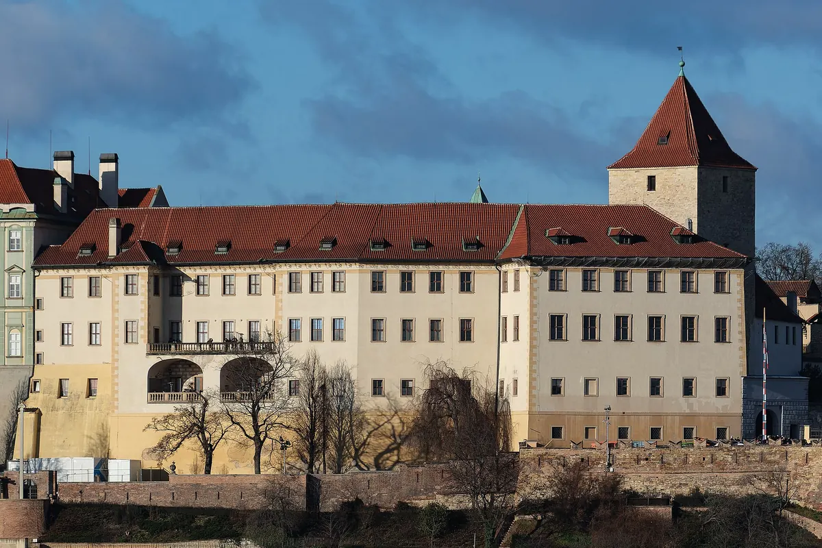 The Lobkowicz Palace and the dark tower beside it on the castle hill, seen from across the river in low sun.